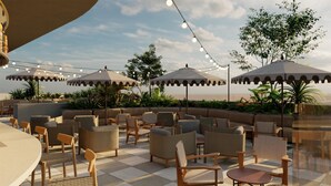 An outdoor seating area with multiple umbrellas, chairs, and tables, surrounded by greenery and plants. - Hyatt Centric Queretaro (Querétaro)