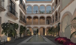 A courtyard with a central water feature, stone walls, and multiple balconies. - Hyatt Centric Queretaro (Querétaro)