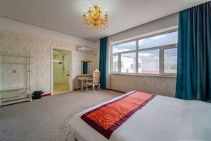 Une chambre d’hôtel avec un lit, un bureau, une chaise, un lustre et une grande fenêtre.