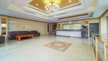 A spacious lobby with a reception desk, sofas, and a chandelier.