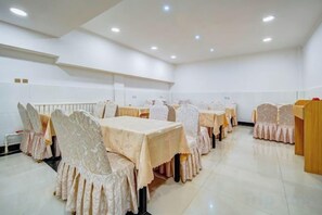 Une salle de banquet avec des tables et des chaises, un podium et un sol carrelé de carreaux blancs.