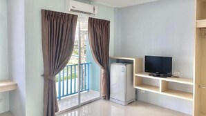 Une chambre avec balcon, une télévision et un réfrigérateur.