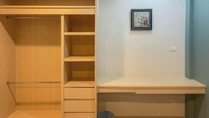 Une pièce avec une armoire en bois, un bureau et un tableau encadré accroché au mur.