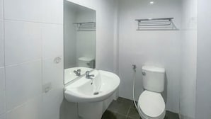 Une salle de bain avec un lavabo blanc, des toilettes et un miroir.