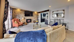 Una sala de estar con pared de ladrillo, chimenea, sofá y televisor.