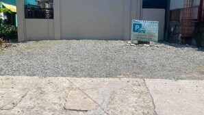 A parking sign with a blue background and white lettering, a gravel surface, and a concrete pavement. - Amplayo Apartelle Studio Type Unit (Cagayan De Oro)