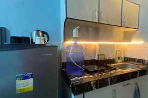 A kitchen with a refrigerator, a sink, and a countertop. - Amplayo Apartelle Studio Type Unit (Cagayan De Oro)