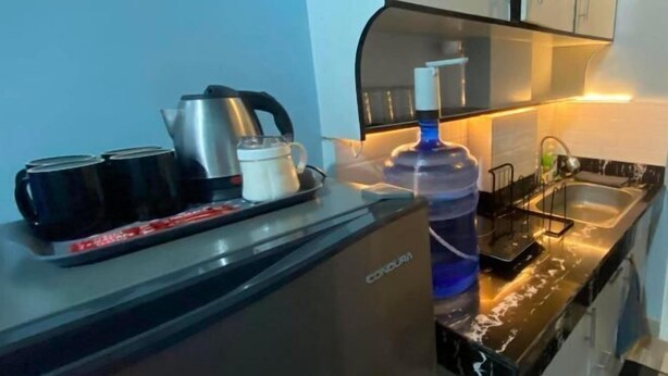 A compact kitchen with a coffee maker, kettle, and a water dispenser. - Amplayo Apartelle Studio Type Unit (Cagayan De Oro)