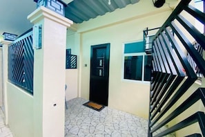 A house with a tiled patio, a black door, and a staircase with black railings. - Amplayo Apartelle Studio Type Unit (Cagayan De Oro)
