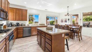 A spacious kitchen with wooden cabinets, a central island, and a dining area with chairs.