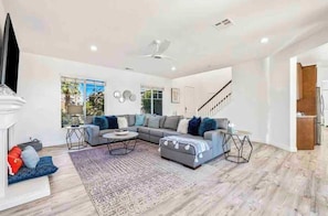 A spacious living room with a sofa set, a coffee table, and a fireplace. - Oasis Escape  - Sleeps 12! Pool-Spa-Ping Pong-BBQ (Indio)