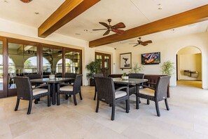 A spacious patio with wicker furniture, ceiling fans, and large windows. - Fairway to Heaven! 3 Bedroom/Sleeps 6! (La Quinta)