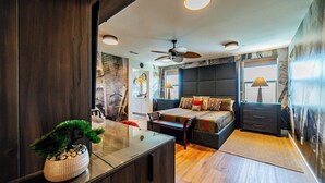 Ein modernes Schlafzimmer mit Bett, Nachttischen, Deckenventilator und einem großen Fenster.