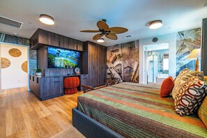 Un dormitorio con una cama grande, televisión, ventilador de techo y vistas al exterior.