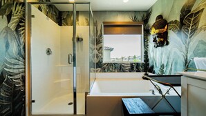 Une salle de bain dotée d’une douche à parois de verre, d’une baignoire et d’une fenêtre offrant une vue agréable.