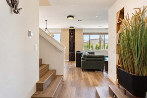 Een modern interieur met een trap, een groene bank en een hoge plant.