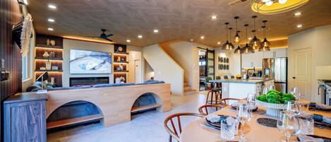 A modern kitchen with a dining area, wooden cabinetry, and a built-in TV.