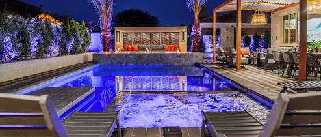 Zona de piscina con sillones de descanso y un espacio de estar con sofá y cojines.