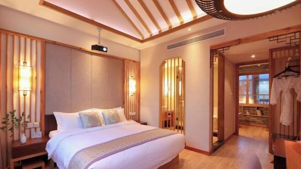 Ein modernes Hotelzimmer mit einem großen Bett, Holzvertäfelung und Blick ins Freie.
