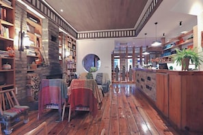 Un interior acogedor con pisos de madera, estanterías, una mesa redonda y una zona de bar.