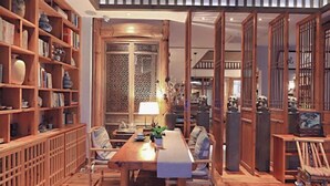 Ein traditioneller japanischer Raum mit Holztisch, Stühlen und einem Bücherregal voller Bücher und Dekorationsgegenstände.