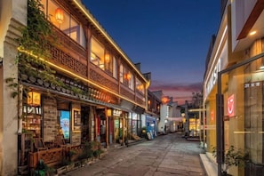 Una calle estrecha con arquitectura tradicional, tiendas y zonas de mesas al aire libre.
