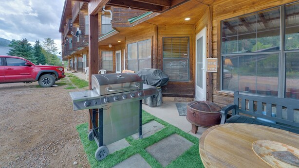 A wooden cabin with a covered patio, a barbecue grill, and a red truck parked outside. - Mtn Views: Waterfront Red River Studio (Red River)