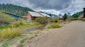 A rural setting with a house, a dirt path, and a stream. - Mtn Views: Waterfront Red River Studio (Red River)