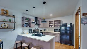 A modern kitchen with a central island, bar stools, pendant lighting, and built-in cabinetry. - Mtn Views: Waterfront Red River Studio (Red River)
