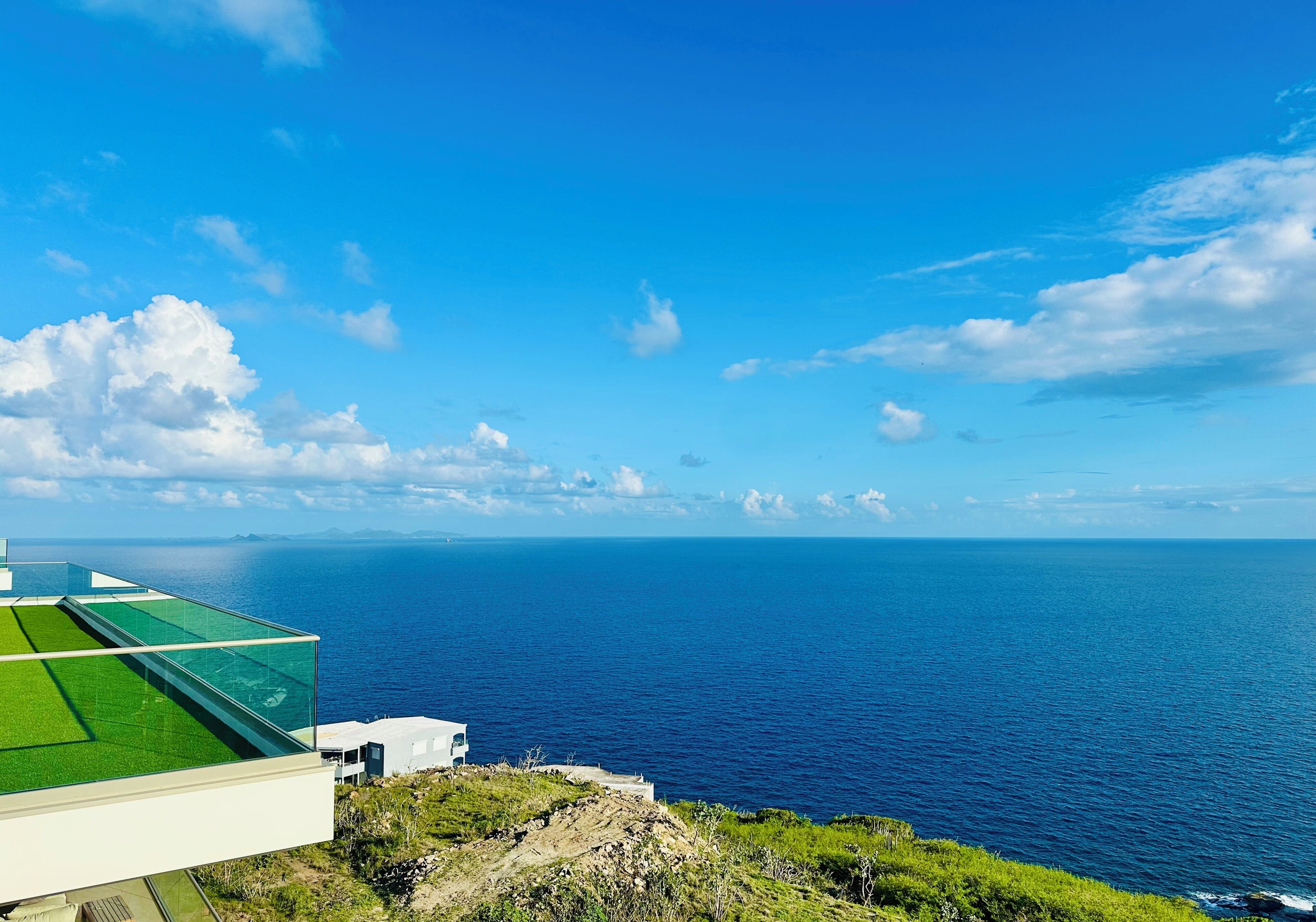 Vista costera con cielo despejado, una masa de agua y un edificio con techo de cristal que da al mar.