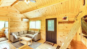 A cozy cabin interior with a sofa, coffee table, and a TV. - 5 Mi to Susquehanna Boating! Secluded Log Cabin (Winfield)