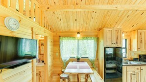 A wooden cabin interior with a dining table, wooden stools, a television, a sink, and cabinets. - 5 Mi to Susquehanna Boating! Secluded Log Cabin (Winfield)