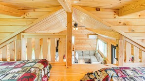 A wooden attic bedroom with two beds, a ceiling fan, and a view of a living area below. - 5 Mi to Susquehanna Boating! Secluded Log Cabin (Winfield)