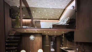 A modern interior with a dining area, kitchen, and loft bedroom. - The HH Point (Tirana)