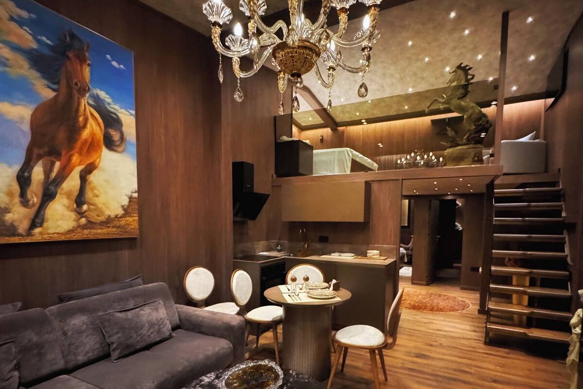 A modern living room with a chandelier, a sofa, a coffee table, and a painting of a horse.