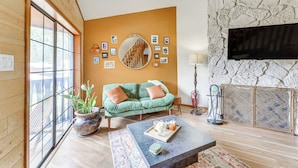 Un salón acogedor con un sofá verde, una mesa de centro y una pared de piedra con un televisor montado.