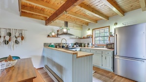 Una cocina con vigas de madera, una isla central y un refrigerador de acero inoxidable.