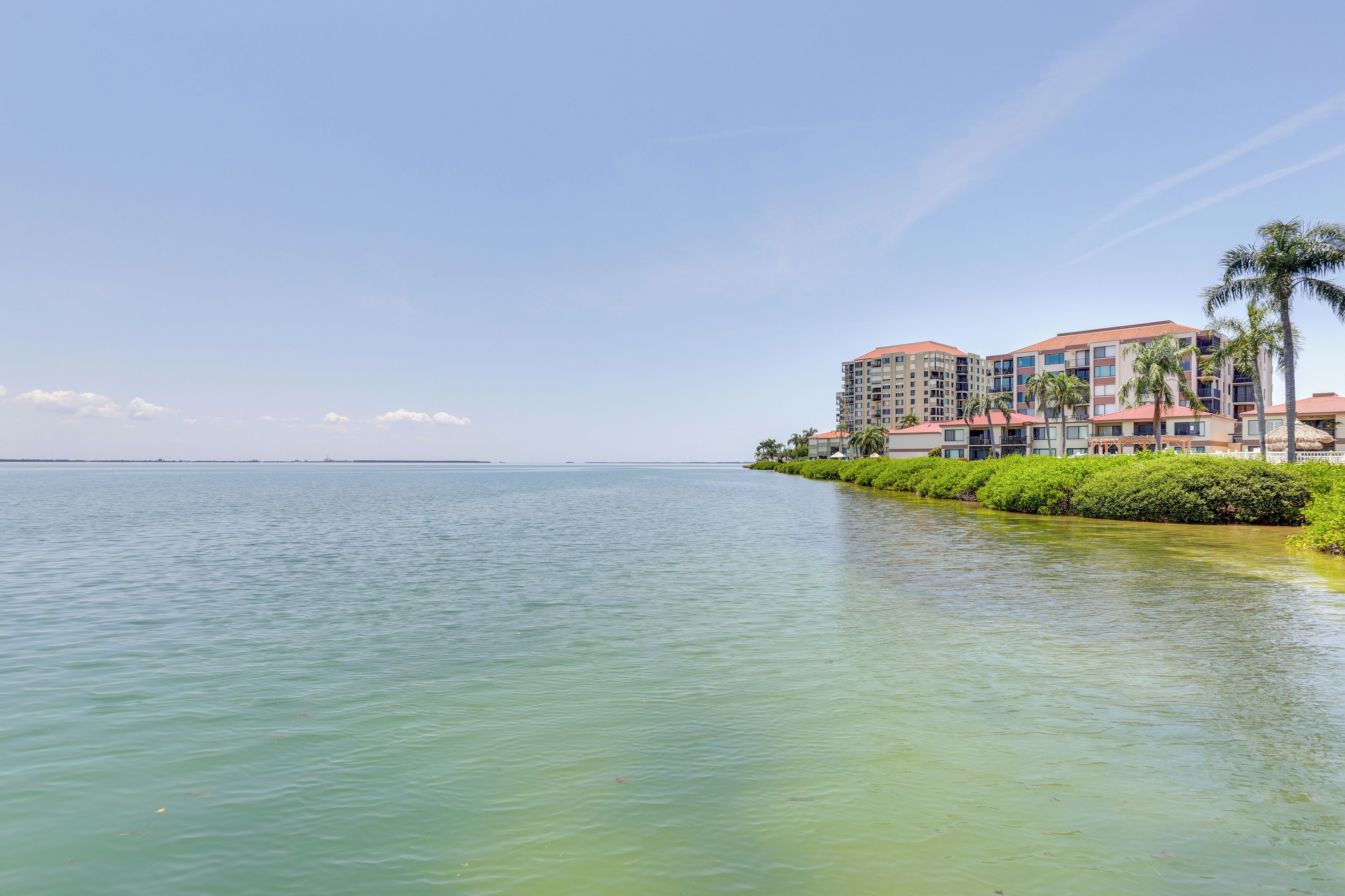 Ein Hotel am Wasser mit mehreren Gebäuden, freiem Blick auf das Wasser und einem gepflegten Strand.