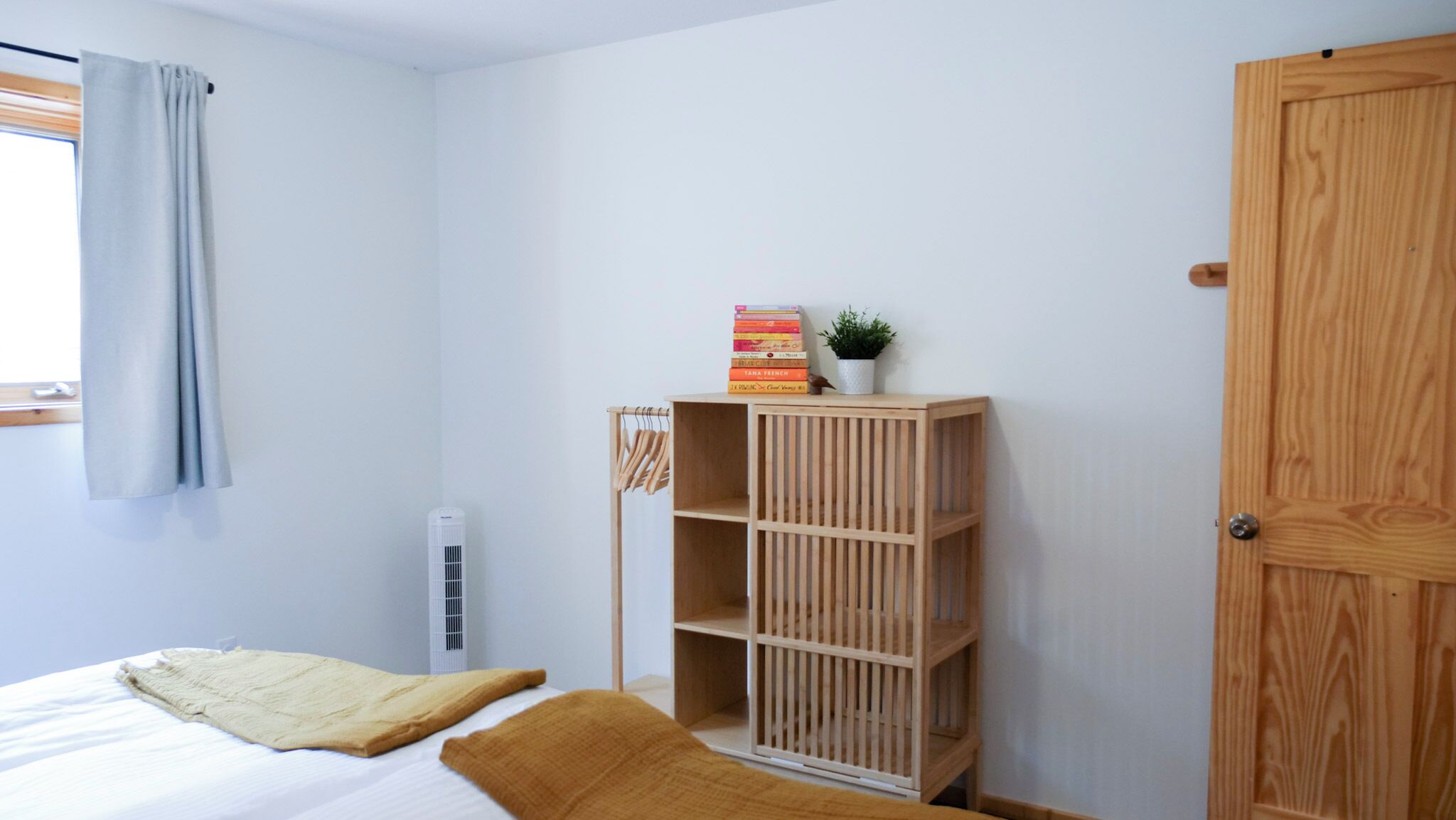 A bedroom with a bed, a wooden bookshelf, a radiator, and a door.