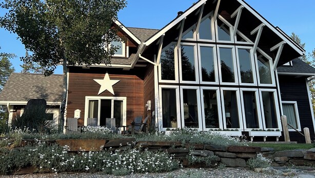 Ein modernes Haus mit einem großen Stern an der Vorderseite, einer verandaartigen Veranda mit großen Fenstern und einem Schotterweg.