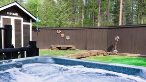 Ein Garten mit Whirlpool, Picknicktisch und Holzlattenzaun mit Schildern.