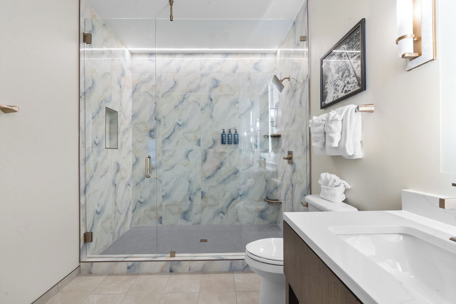 A modern bathroom with a glass-enclosed shower, a white toilet, and a marble backsplash.