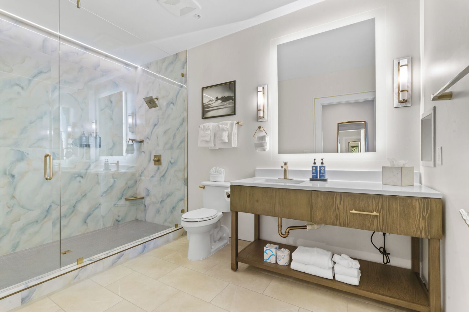 A modern bathroom with a marble shower enclosure, a wooden vanity, and a large mirror.