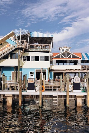A waterfront building with a dock, a staircase leading to the upper level, and a sign reading "Landshark Lookout." - Harbor Suites at Harborwalk Village (Destin)