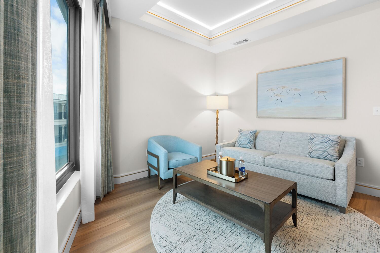 A modern living room with a sofa, a chair, a coffee table, and a lamp.