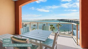 Un balcón con mesa y sillas, con vistas a un puerto deportivo con barcos y un muelle.