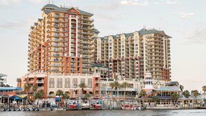 Un hotel frente al agua con varios edificios altos, balcones y un puerto deportivo con barcos.