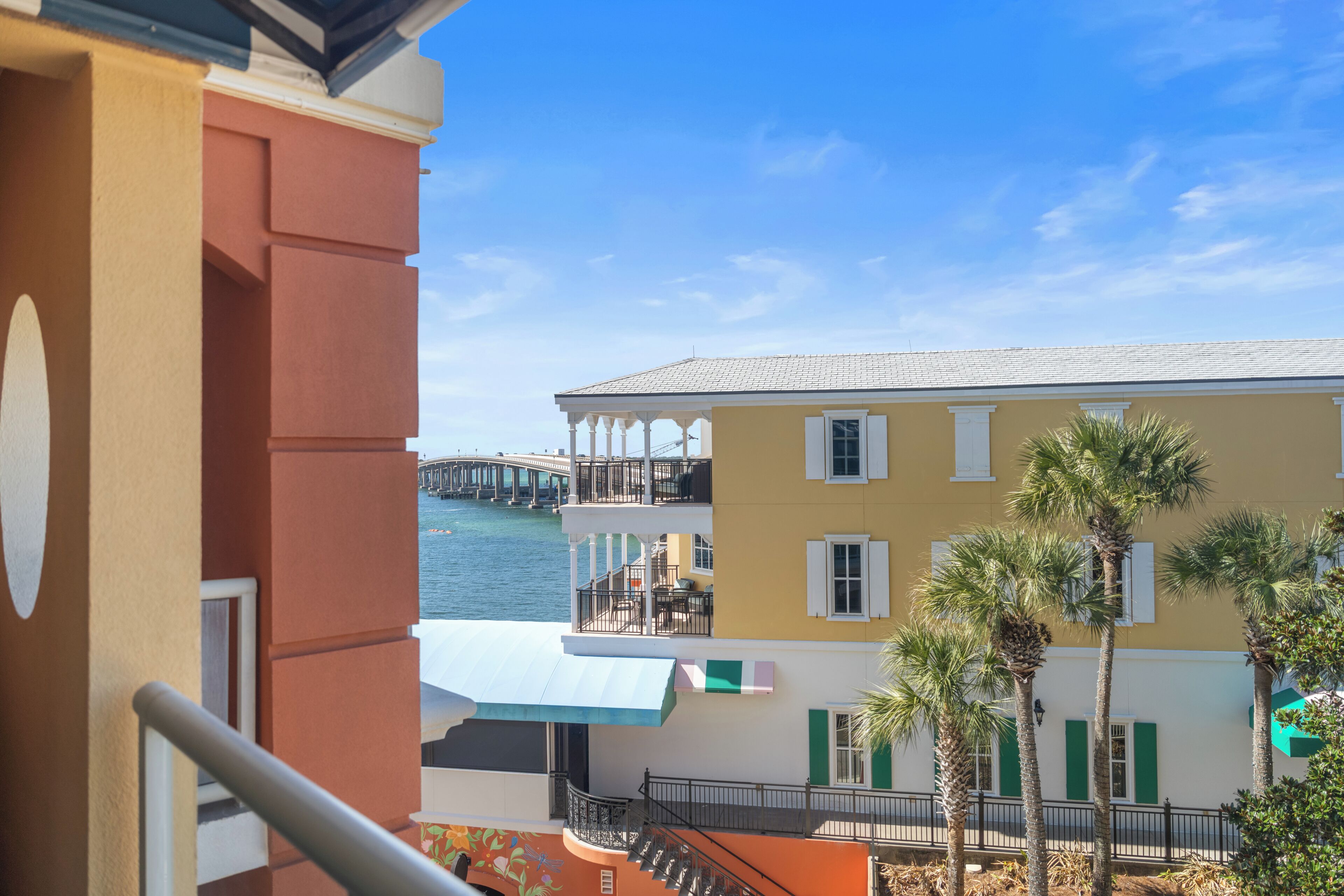 Un edificio de varios pisos con balcones, vista al agua y palmeras.