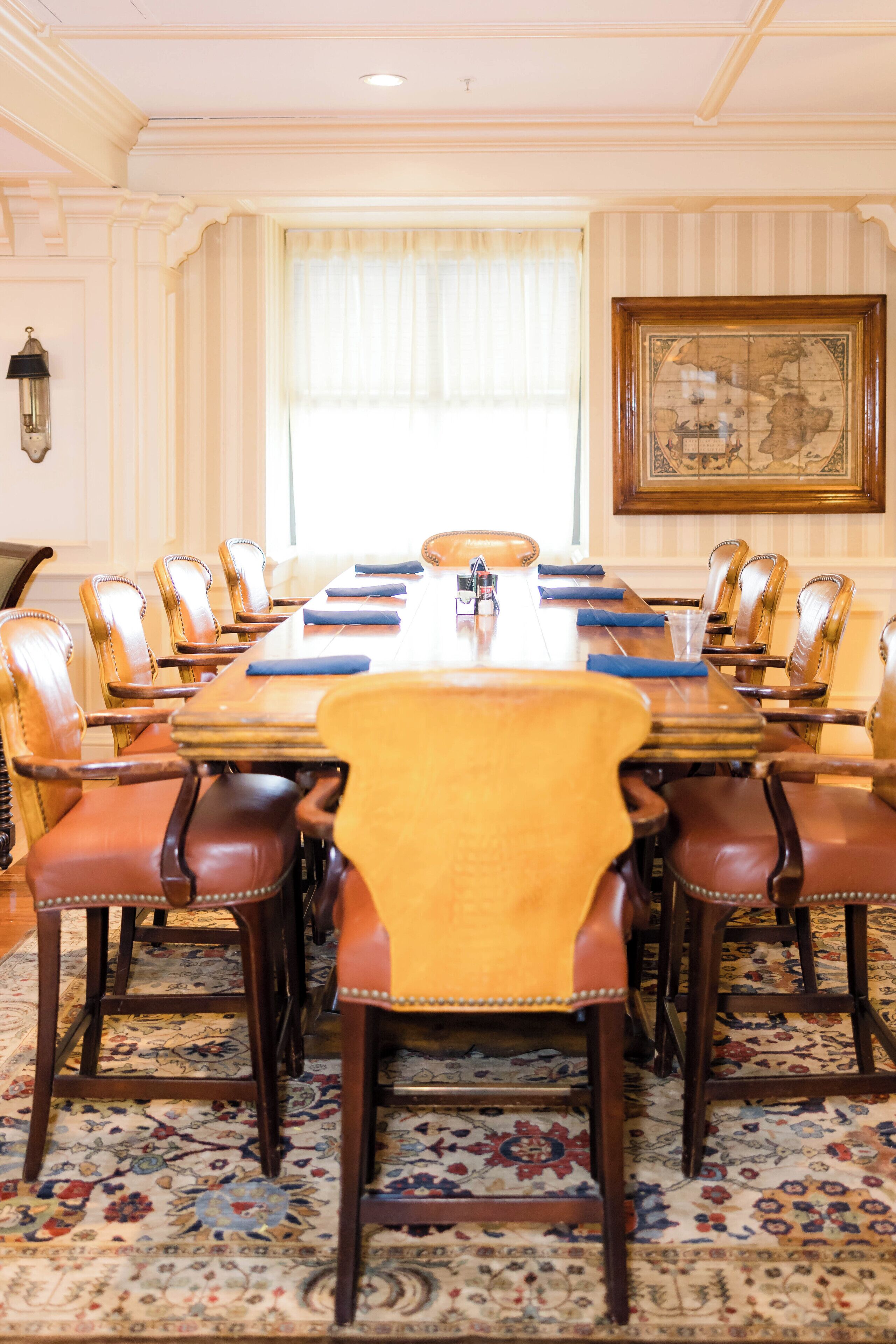 A conference room with a long table, leather chairs, and a patterned carpet.