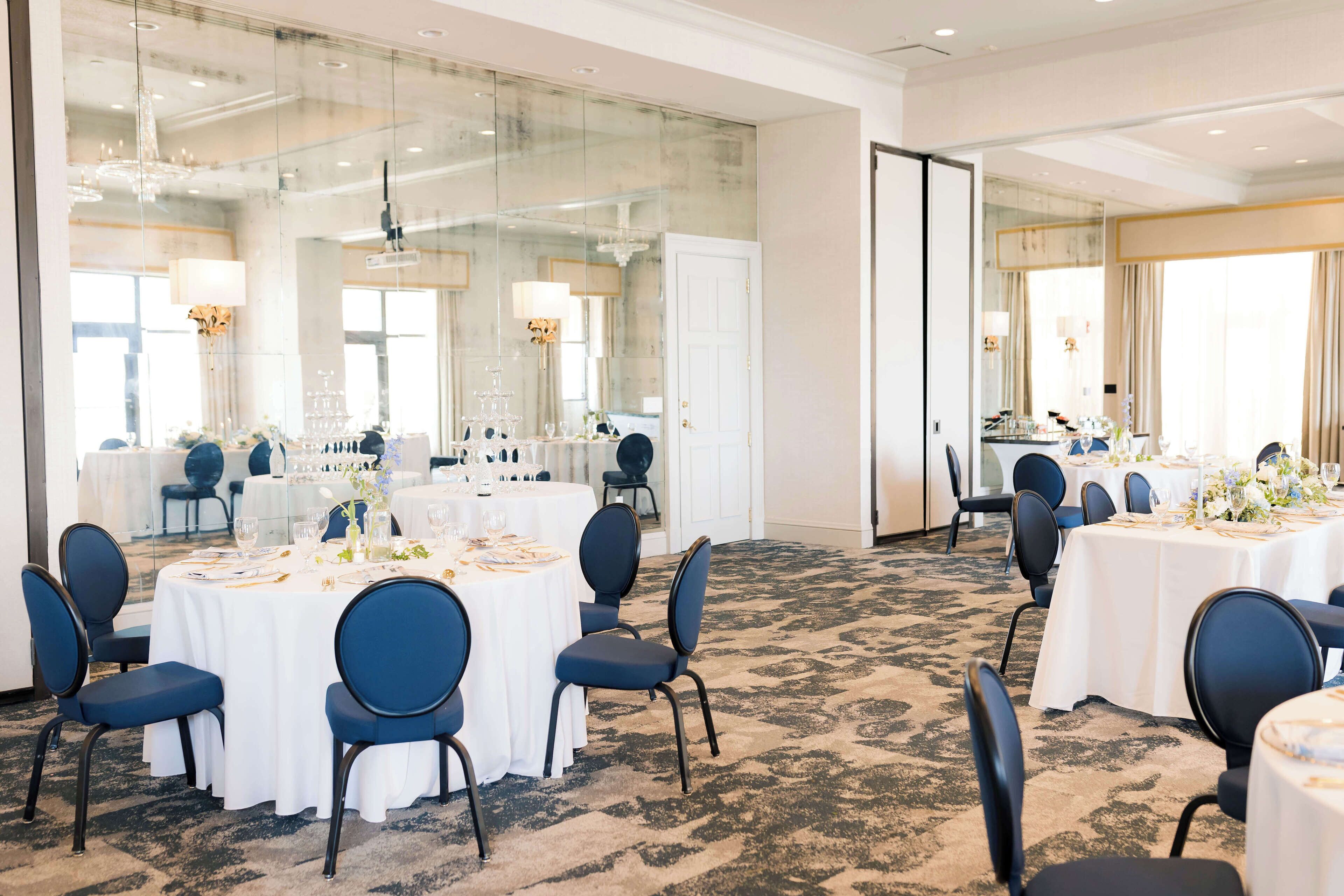 A conference room with multiple tables set for dining, equipped with chairs and table settings.